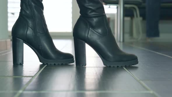 Girl struts in front of the camera in black faux leather high heels block heel boots around