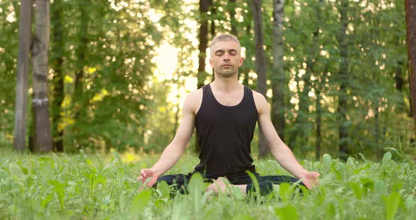 Men Sitting on Grass in Lotus Pose Meditating Outdoors at Sunrise