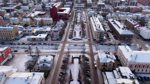 Aerial forward tilt-up reveal view of snowy Sundsvall Swedish cityscape at dusk, Sweden