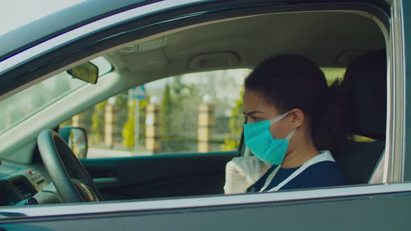 Female Driver Disinfecting Steering Wheel with Hand Sanitizer