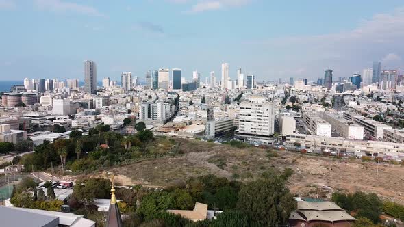 Aerial downward shot revealing a church steeple in front of city buildings view, park and sky, on a