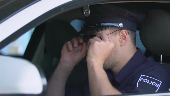 Respectable Police Officer in Uniform Wearing Sunglasses Sitting in Car, Patrol