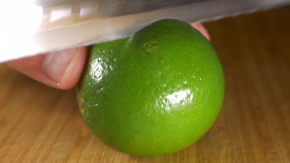 CLOSE UP, Lime Cut In Half With Serrated Knife On Wooden Board