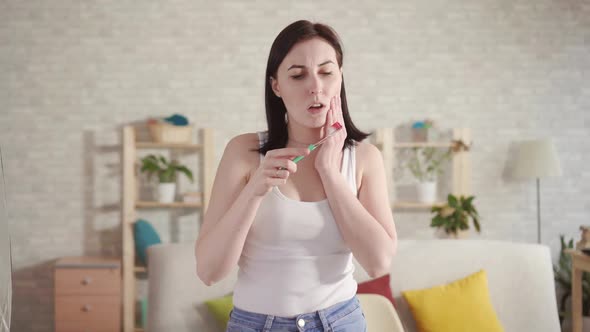 Young Woman Notices Blood on the Brush and Mouth Pain While Brushing Her Teeth