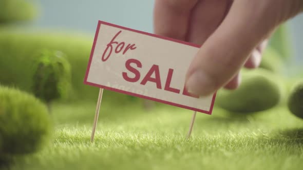 Sign For Sale in an Area with Green Grass Trees and Hills