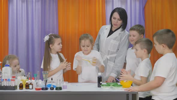 Chemical Experiments for Children. Children Shake a Transparent Flask with a Yellow Liquid, Closed