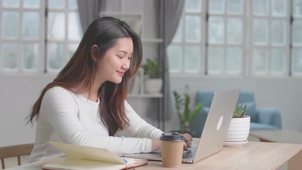 Happy Asian Girl Typing On Computer Keyboard Of A Laptop At Home