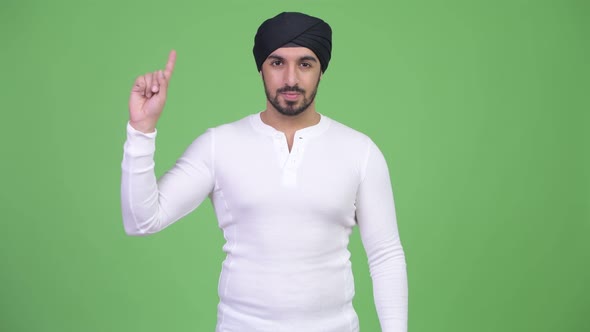 Young Handsome Bearded Indian Man Pointing Up