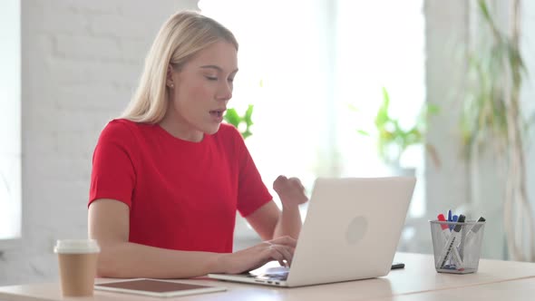 Young Blonde Woman Coughing while using Laptop in Office