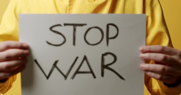 Person Holding a White Paper with a Message Stop War