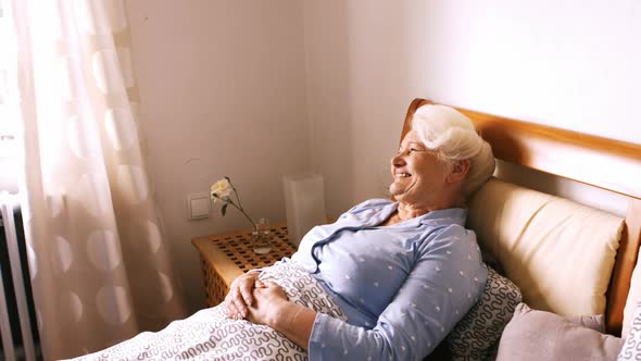 Nurse interacting with senior woman on bed