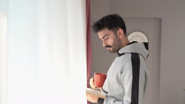 Man walking around the house and reading a book.