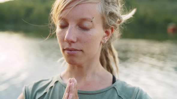 Woman Meditating with Eyes Closed near the Lake