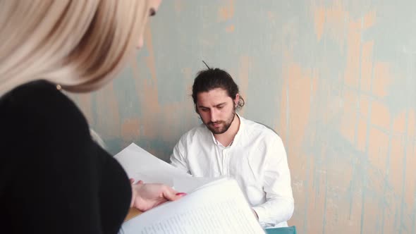 Young Woman Office Worker Close Up Work with Papers and Her Male Collegue at the Background