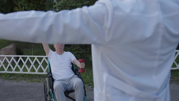 Attentive Old Man Does Some Exercises After Doctor