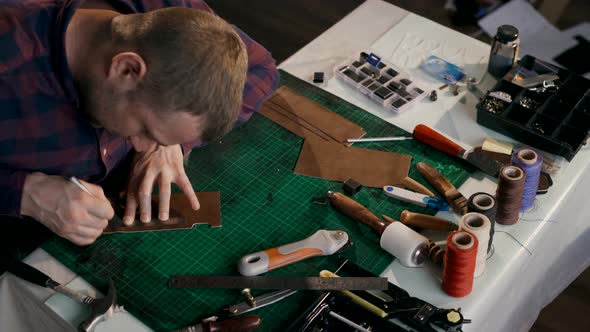 The Process of Manufacturing a Leather Wallet Handmade. The Craftsman Cut Off a Piece of Leather