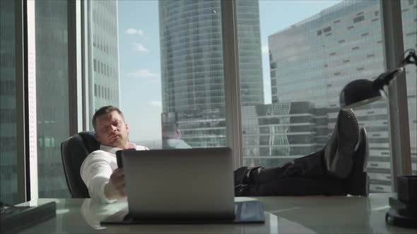 A Man in a White Shirt Has Put His Feet on the Desk