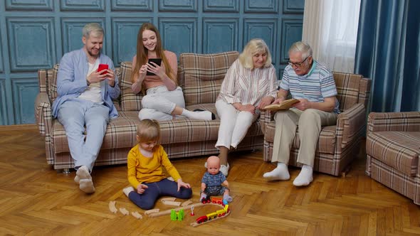 Multigenerational Family Leisure at Home Talking Reading Book Use Mobile Phone Play Game on Sofa