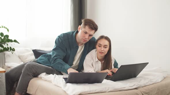 Young Caucasian Couple Work Together at Home Using Laptop.