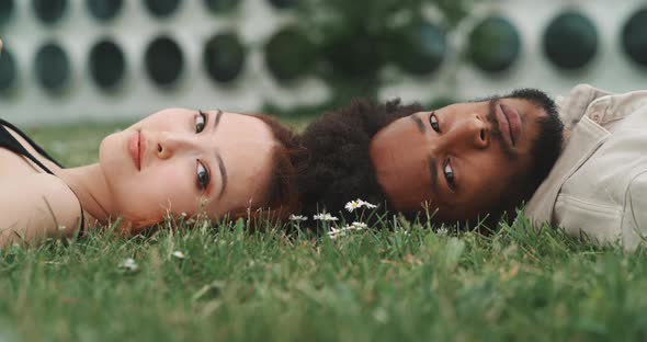 A young couple lying on the ground and looking at the camera