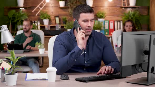 Office Worker Having a Phone Conversation in Modern and Cozy Office