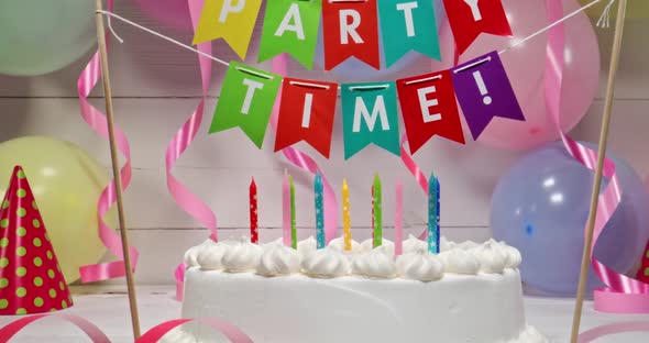 Birthday cake with candles on background of balloons and ribbons.