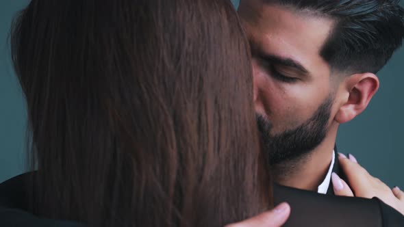 Blackhaired Handsome Man in a Suit with Facial Hair Coming Closer to a Longhaired Woman with Long