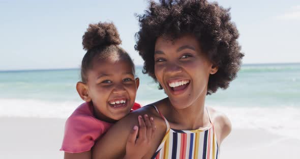 Portrait of smiling african american mother and daughter on sunny beach