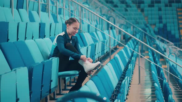 Sports Arena with a Young Girl Lacing Up Her Ice Skating Shoes