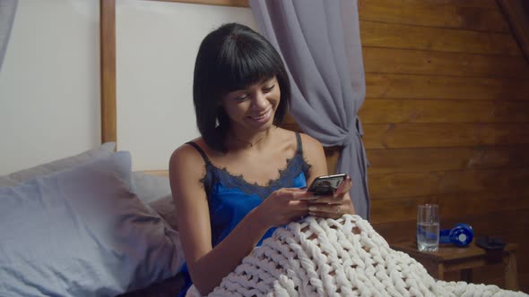 Positive Female Networking with Smartphone in Bed