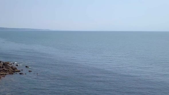 STATIC CROP, Aerial, flying out into the ocean past Jurassic Coast red cliffs