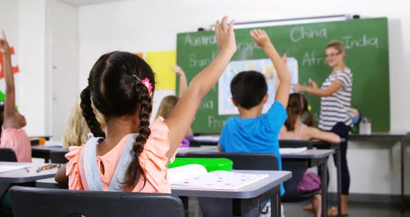 School kids raising hand in classroom