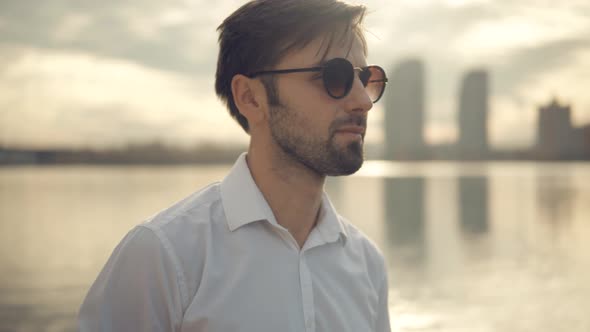 Man Walking On City Beach. Cheerful Romantic Guy In Sunglasses Walks On Sand And Dreaming.