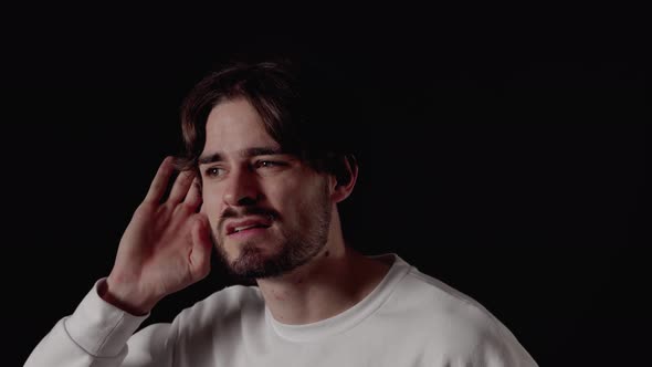 Trendy Young Man listening with hand, deaf gesture, close, black background