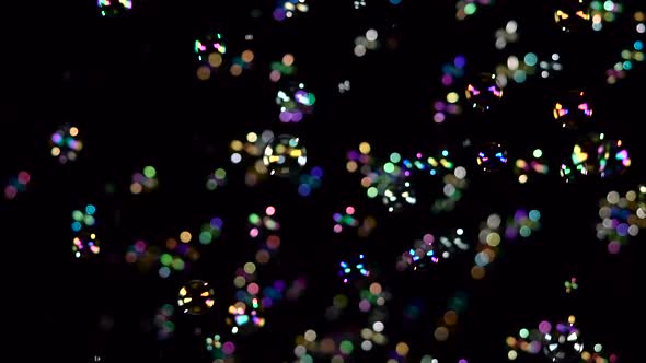 Soap Bubbles Fly and Fade in Different Colors. Slow Motion. Black Background