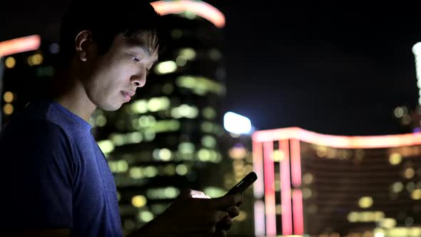 Asian man use of mobile phone at night 