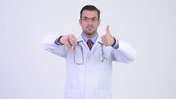 Young Happy Hispanic Man Doctor Choosing Between Thumbs Up and Thumbs Down