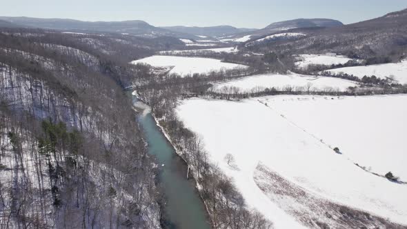 Aerial of Rolling Hills And River With Snow