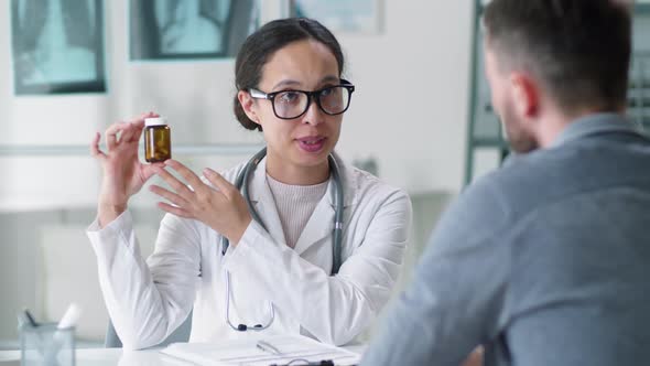 Young Female Physician Giving Pills to Male Patient on Consultation