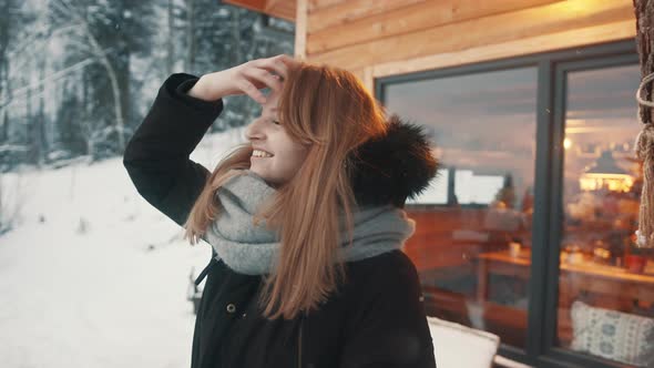 Beautiful Young Woman Adjusting Her Long Hair in Front of the Wooden Mountain House and Enjoying