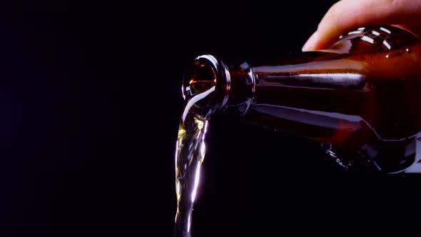 Beer Is Poured From Dark Glass Bottle. Slow Motion, Closeup