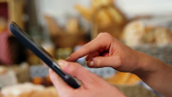 Mid section of woman using digital tablet at bakery section