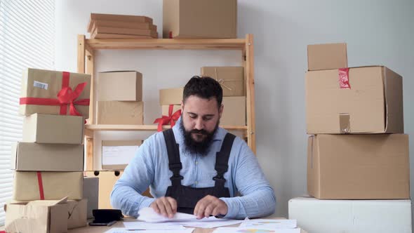 Indian Male Entrepreneur Online Store Warehouse Worker Resting at Workplace Having Fun Making Paper