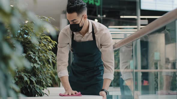 Arab Man Worker Hispanic Male Waiter in Medical Mask Catering Worker in Apron Wipes Table Splashing