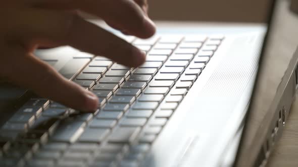 A man presses his fingers on the keyboard of a laptop