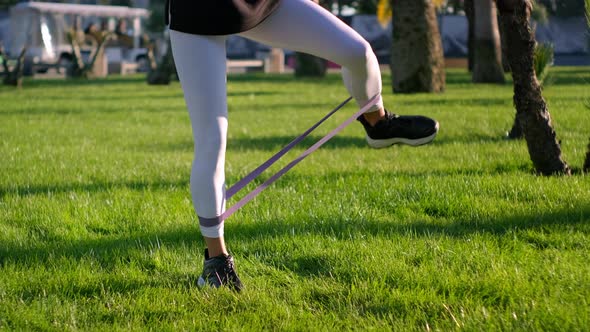 Sport Outdoors Woman is Training Legs with Tape