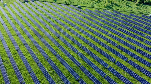 Aerial view on Solar Power Station in Green Field near River at Sunny Day