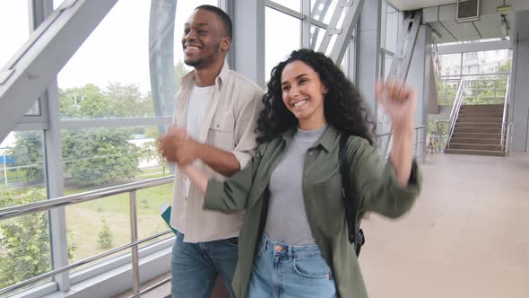 Multiracial Couple Afro Man and Hispanic Wife Holding Hands Carrying Suitcase Luggage Walking in