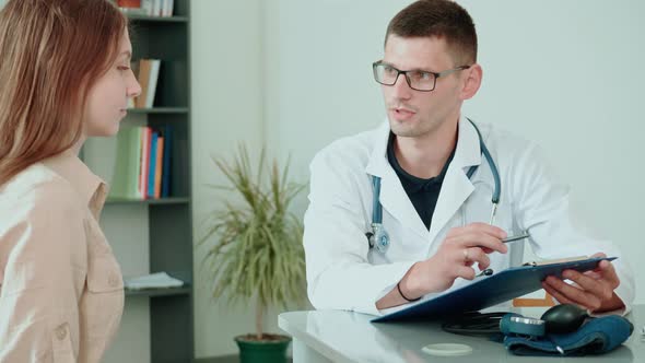 Male Doctor Examining and Consulting Young Woman in the Hospital. Consulting of Patient at Clinic.