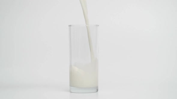 Slow Motion of Pouring Milk in Transparent Glass White Background